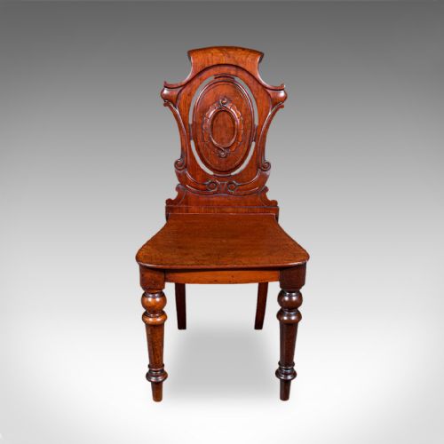 fig 1. A Victorian walnut hall chair with a carved shield back, solid wood seat, turned front legs, and swept rear legs.