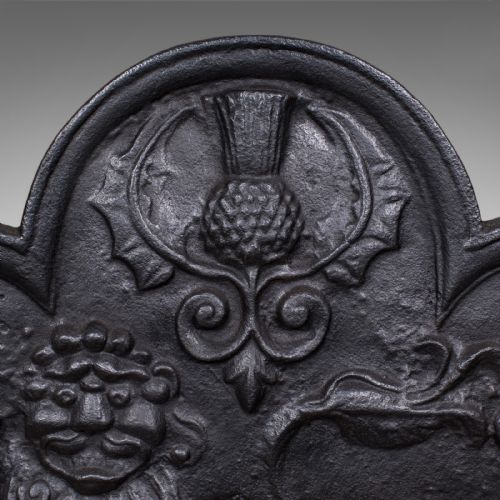 fig 3. An arched cast iron fire back decorated with a central lion relief, a thistle motif at the apex, and fleur-de-lis accents.