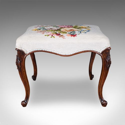 fig 1. An Early Victorian walnut footstool featuring cabriole legs and a cream upholstered top detailed with a floral needlepoint design.