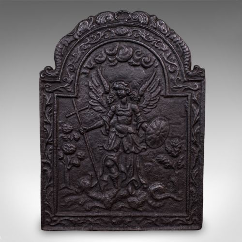 fig 1. A heavy arched Victorian cast iron fireback featuring an embossed relief depicting an angelic figure with a cross and shield framed by detailed scrollwork borders.