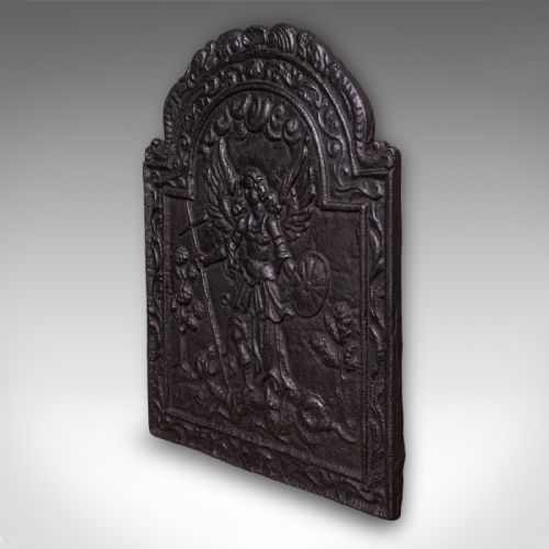 fig 2. A heavy arched Victorian cast iron fireback featuring an embossed relief depicting an angelic figure with a cross and shield framed by detailed scrollwork borders.