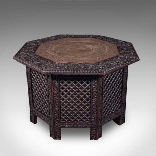 fig 2. An octagonal dark wood Anglo-Indian tea table featuring deeply carved lattice work side panels and an engraved copper inset top.