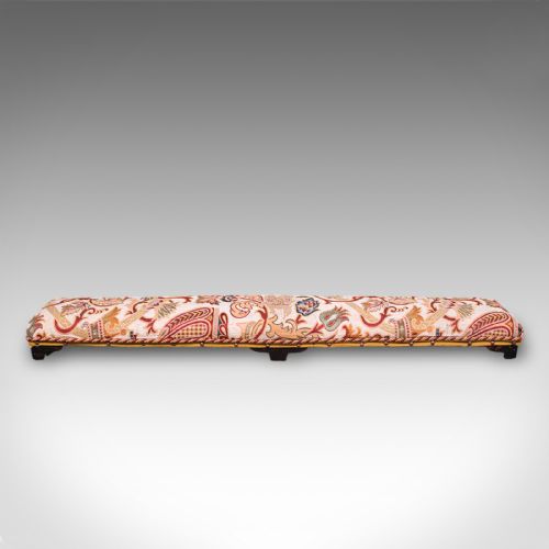 fig 1. An elongated Victorian carriage stool featuring multicoloured crewelwork floral upholstery with braid trim and short turned dark wooden legs.