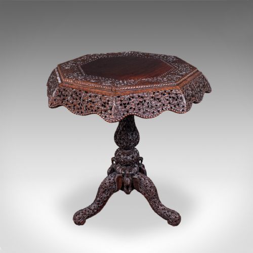 fig 1. An octagonal Victorian Burmese teak side table featuring intricate relief carving throughout the top apron, central stem, and tripod legs.