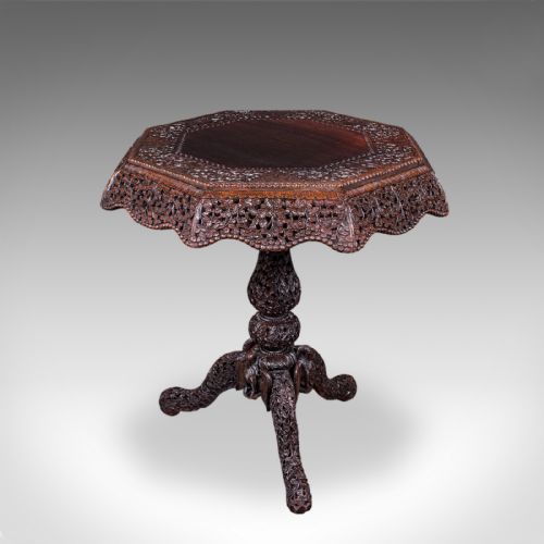 fig 2. An octagonal Victorian Burmese teak side table featuring intricate relief carving throughout the top apron, central stem, and tripod legs.