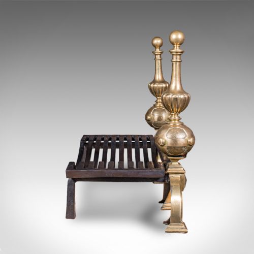 fig 2. A Victorian cast iron fire grate mounted between two tall brass firedogs featuring orb finials and splayed feet.