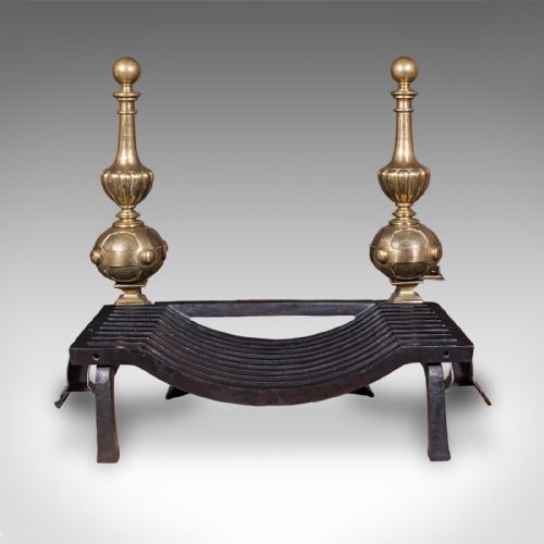 fig 3. A Victorian cast iron fire grate mounted between two tall brass firedogs featuring orb finials and splayed feet.