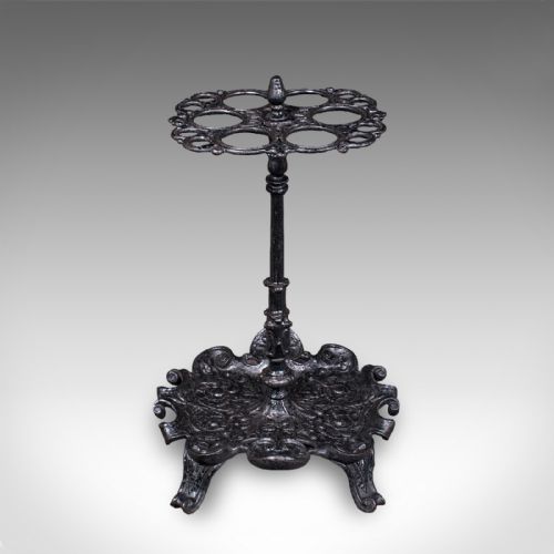 fig 1. A Victorian cast iron stick stand featuring a central column, a six-loop upper ring, and a decorative scrollwork base with integrated drip tray in a dark finish.