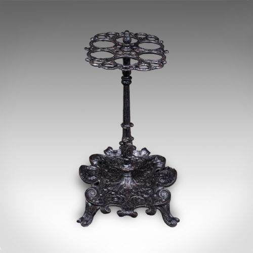 fig 2. A Victorian cast iron stick stand featuring a central column, a six-loop upper ring, and a decorative scrollwork base with integrated drip tray in a dark finish.