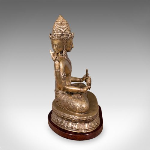 fig 2. An antique bronze multi-headed and four-armed Balinese deity figure seated in lotus position on a lotus base, mounted on an oval wooden plinth.