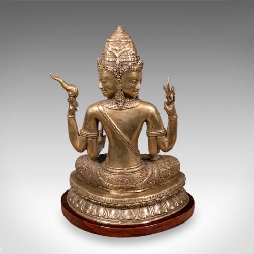 fig 3. An antique bronze multi-headed and four-armed Balinese deity figure seated in lotus position on a lotus base, mounted on an oval wooden plinth.