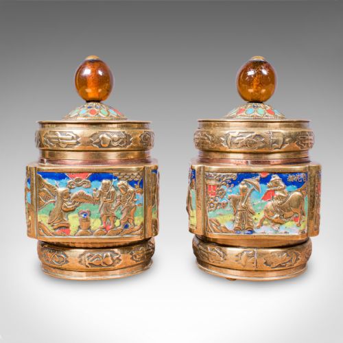 fig 2. A pair of Edwardian brass tea caddies featuring polychrome champleve enamel figurative panels and amber-coloured spherical finials.