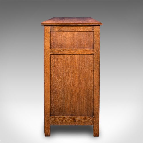 fig 3. An antique Edwardian medium brown oak sideboard featuring three upper drawers with brass drop handles above panelled cupboard doors.