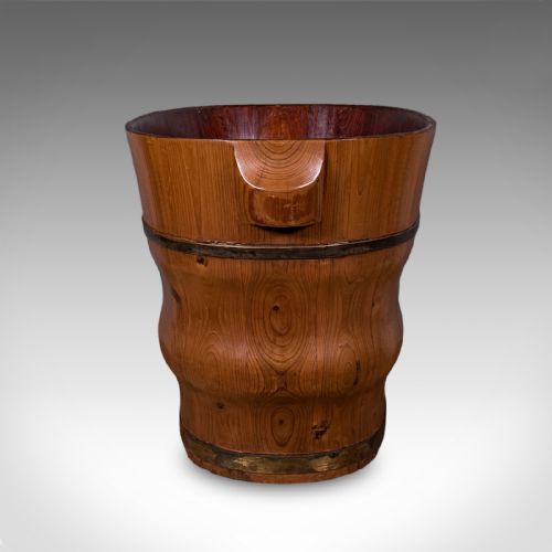 fig 2. An oval late Victorian Dutch cedar waste paper basket with brass binding straps and carved side handles on a light background.