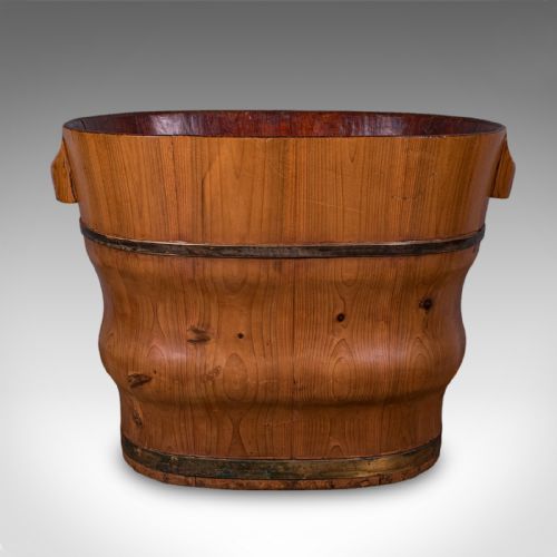 fig 3. An oval late Victorian Dutch cedar waste paper basket with brass binding straps and carved side handles on a light background.