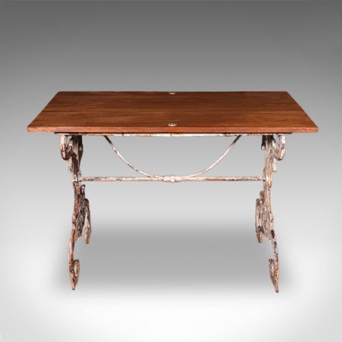 fig 1. A Victorian table featuring an ornate white distressed cast iron scrollwork base and a smooth mahogany top.
