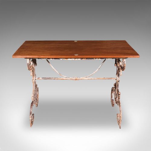 fig 3. A Victorian table featuring an ornate white distressed cast iron scrollwork base and a smooth mahogany top.