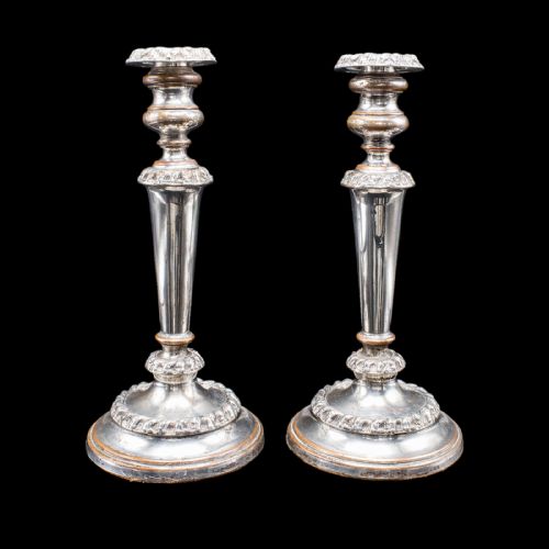 fig 1. A pair of Regency period Old Sheffield plate silver candlesticks featuring tapered columns, gadrooned borders, and circular bases with copper undertones.