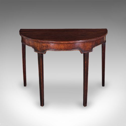 fig 1. An antique dark mahogany demi-lune console table featuring tapered legs and a curved frieze.