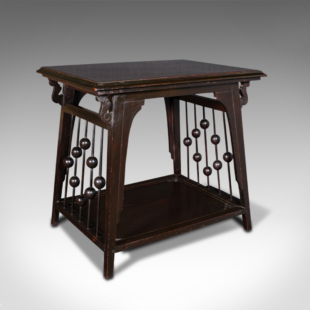 An Aesthetic Movement ebonised wood two-tier side table featuring side galleries set with turned wooden spheres.