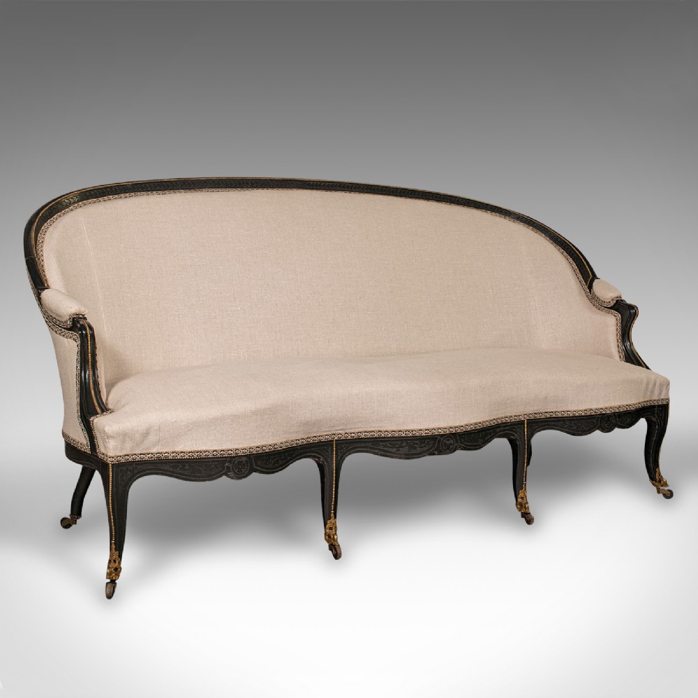 A 19th-century Continental Louis XV style ebonised settee upholstered in neutral linen with gilt accents and cabriole legs on castors.