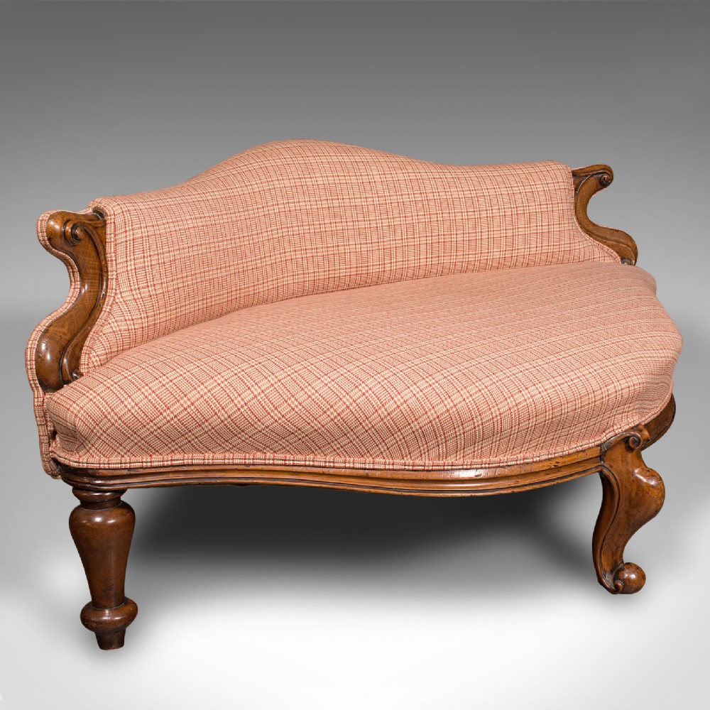A Victorian asymmetrical walnut love seat featuring a carved wood frame and red patterned fabric upholstery.