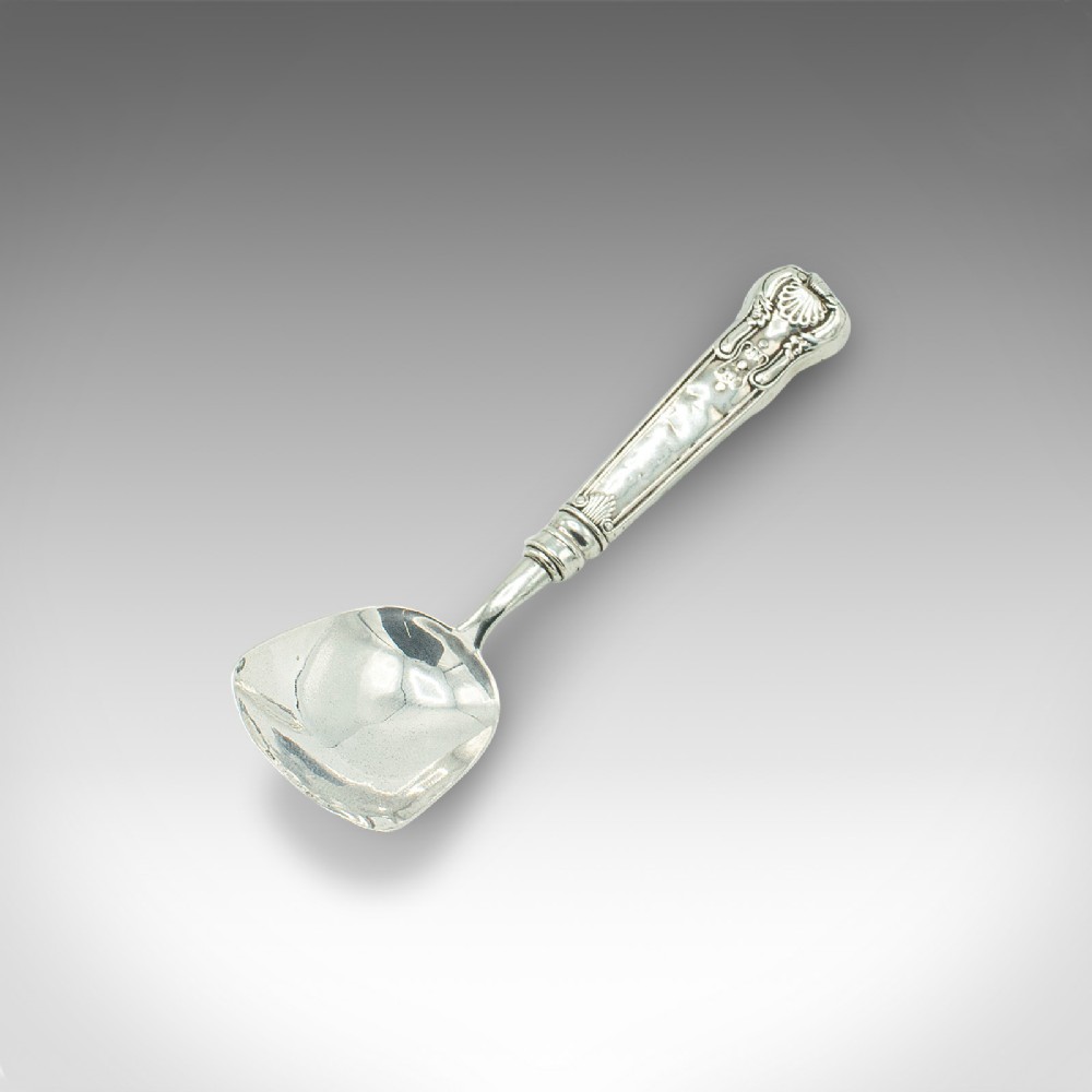 An 18th-century English sterling silver sugar spoon featuring a square shovel-shaped bowl and a shell motif handle.