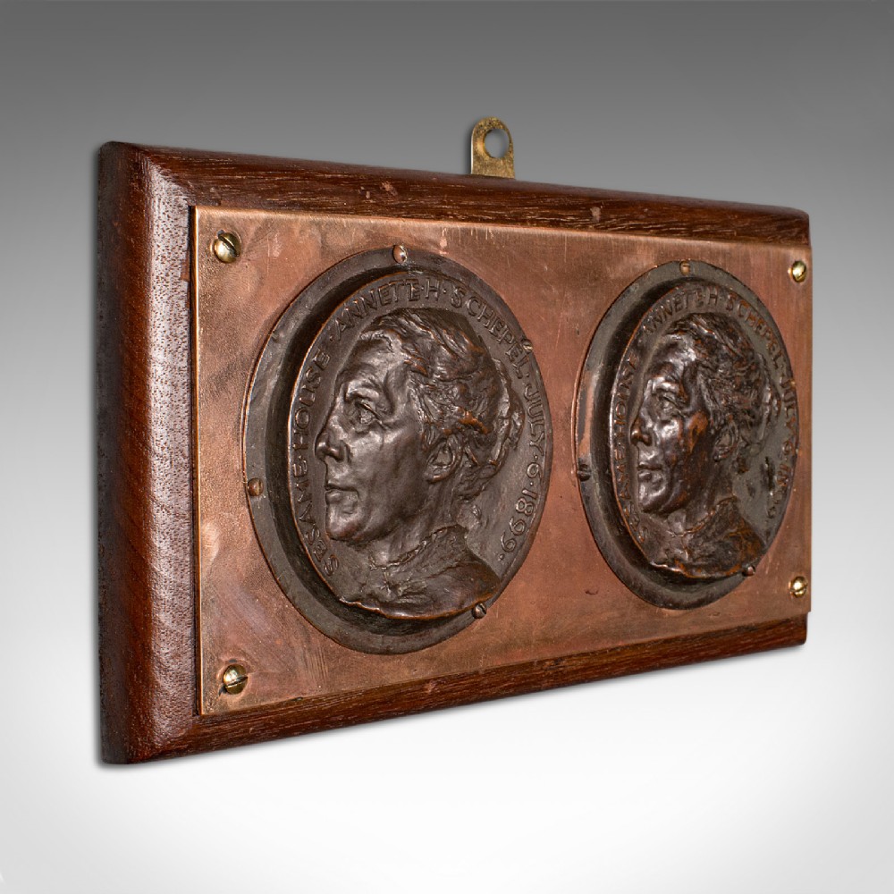 A late Victorian mounted portrait plaque featuring two circular bronze profile medallions set on a copper plate with a mahogany timber mount.