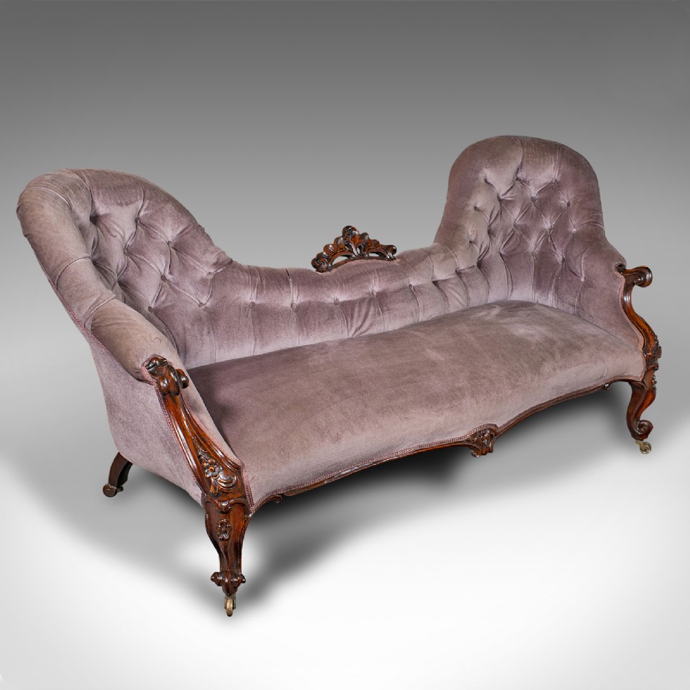 An early Victorian double spoon back settee upholstered in mauve velvet with a carved timber frame and cabriole legs.