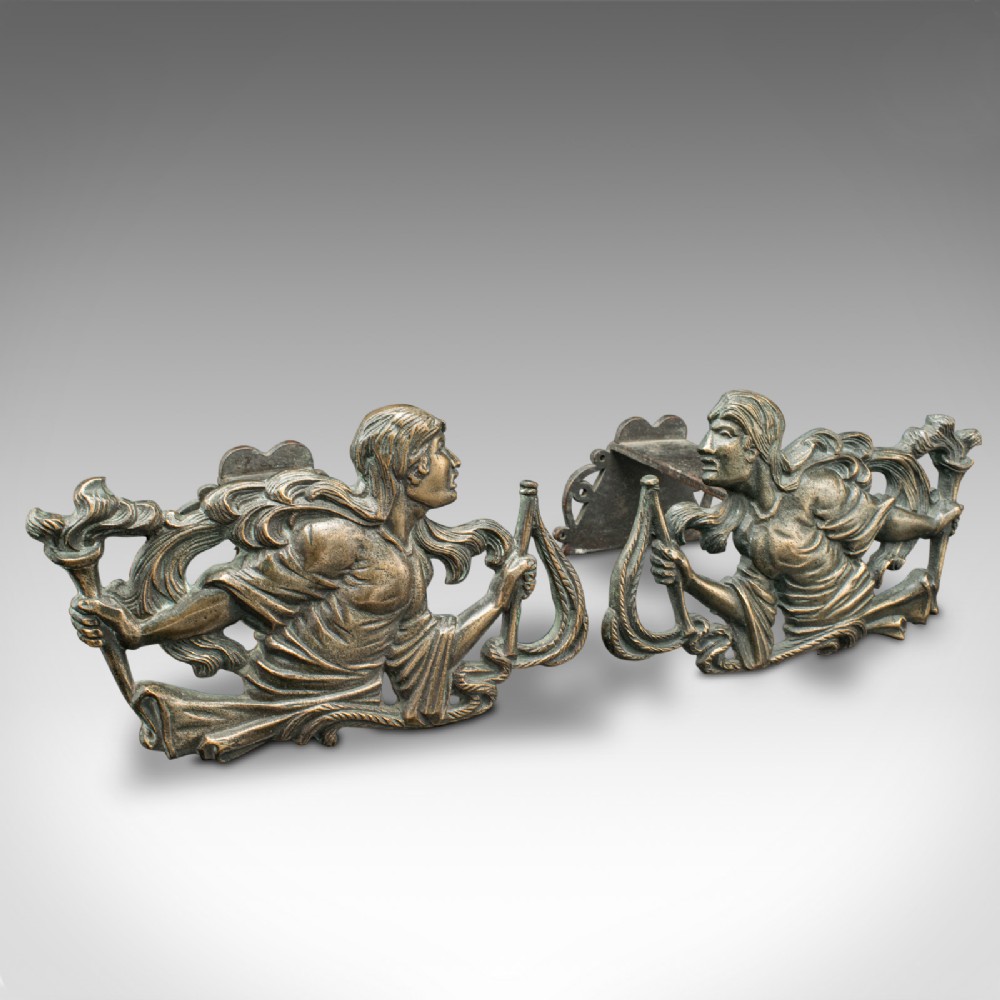 A pair of mid-19th century French bronze figural andirons featuring sculpted classical figures holding torches with iron hearth supports behind.