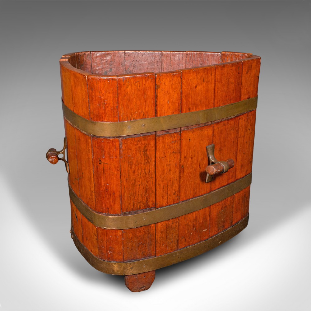 An Early Victorian triangular wooden fireside bin constructed with staves bound by brass bands and side carrying handles.