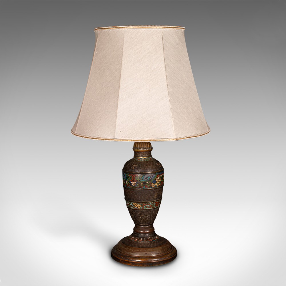 An antique Japanese dark bronze vase-shaped table lamp featuring polychrome cloisonne enamel bands and fitted with a cream fabric shade.