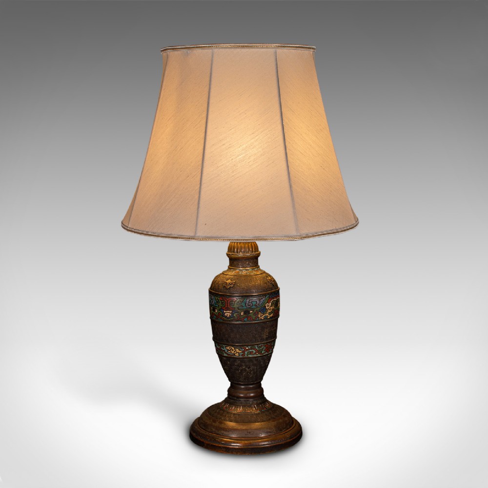 An antique Japanese bronze and cloisonne table lamp with colourful enamelled geometric bands and a light beige fabric shade.