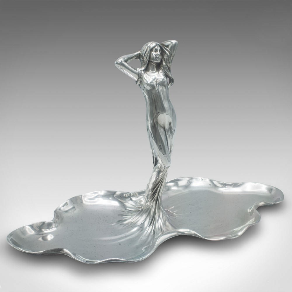 A silver-toned Art Nouveau metal card tray featuring a central sculpted maiden figure with flowing hair standing atop a shaped lily pad base.