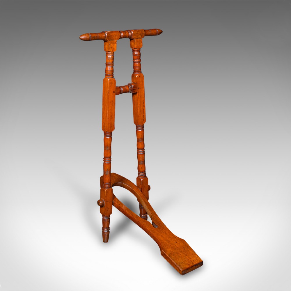 A Victorian walnut standing boot jack featuring turned upright supports, a top handlebar, and a folding foot-operated boot pull mechanism.