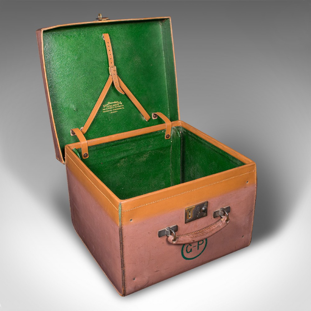 An open antique tan brown leather picnic case with a bright green lined interior, internal straps, brass locking mechanism, and a single carrying handle.