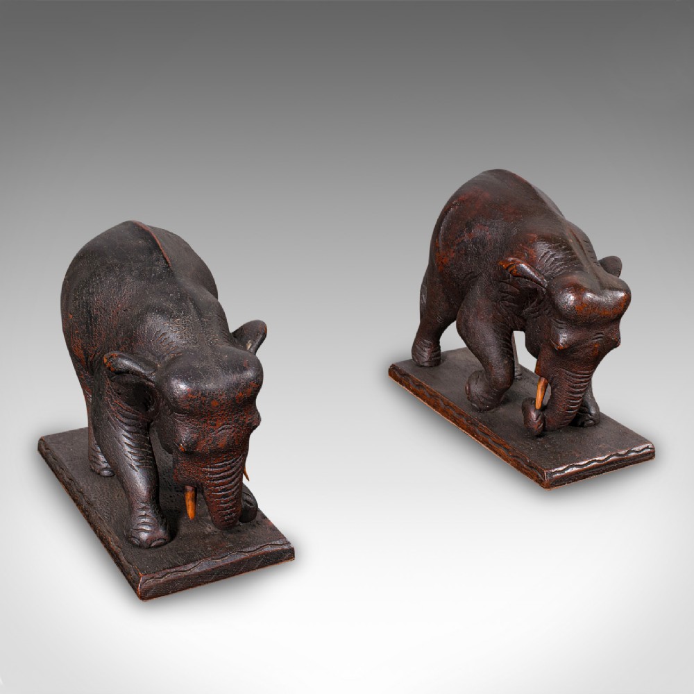 A pair of hand-carved dark hardwood bookends shaped like elephants standing on rectangular wooden bases.