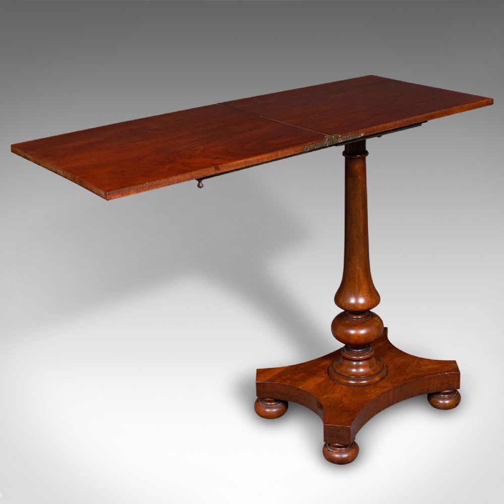 An antique mahogany calligraphers table featuring a hinged cantilevered top supported by a turned pedestal column and a plinth base with compressed ball feet.