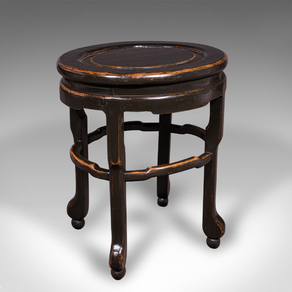 An antique Japanese ebonised elm side table featuring an oval top, shaped stretchers, and curved legs.
