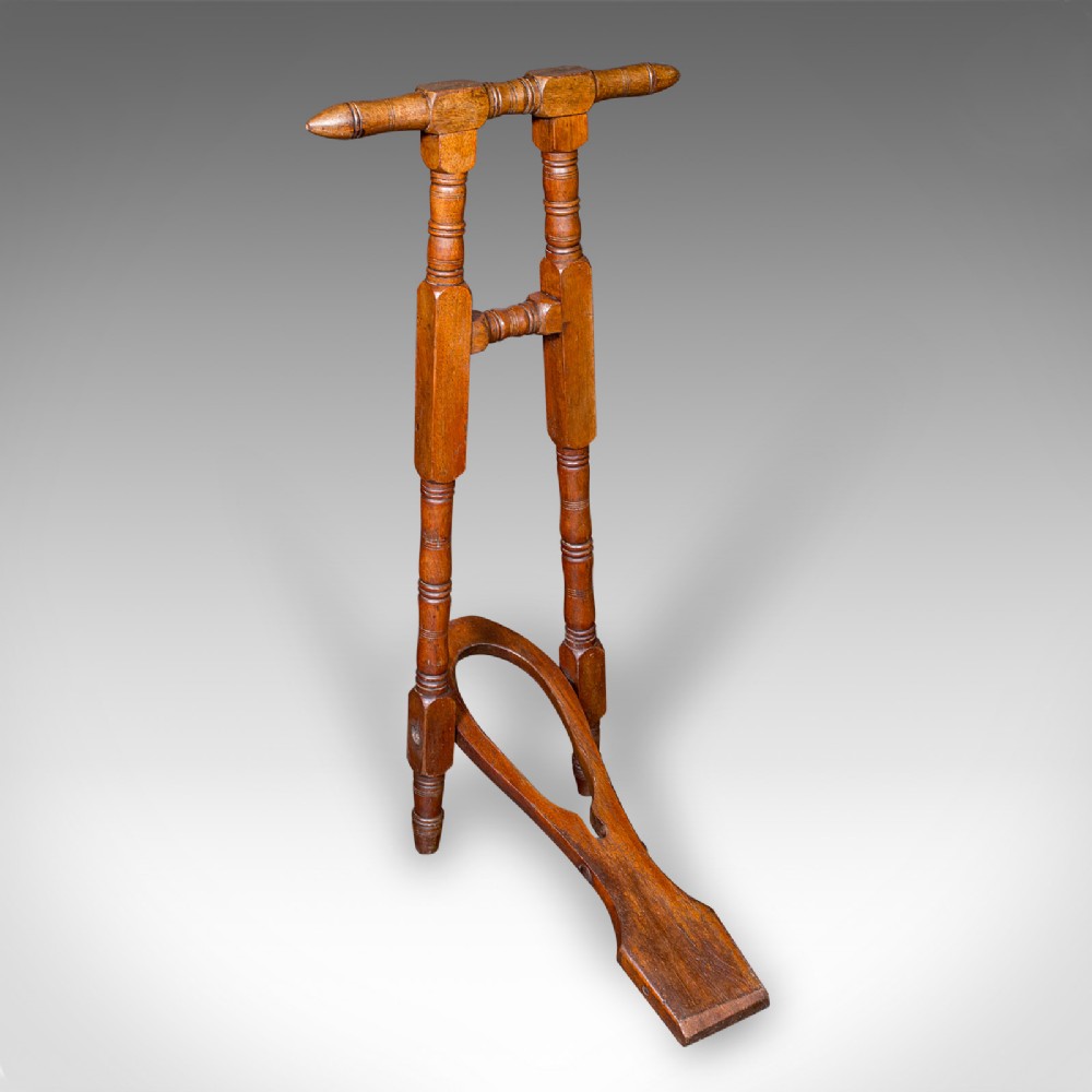 A Victorian turned walnut folding standing boot jack with a top hand grip and a u-shaped heel cutout.