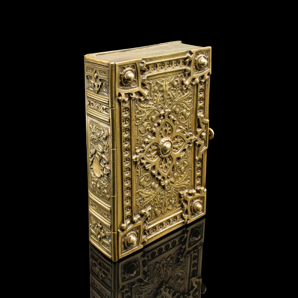 An ornate Victorian cast brass keepsake box fashioned in the shape of a book, featuring relief floral and thistle motifs with corner bosses.