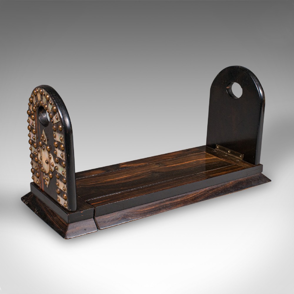 An antique Regency coromandel wood extending book slide featuring mother-of-pearl inlay and brass stud detailing on folding arched ends.