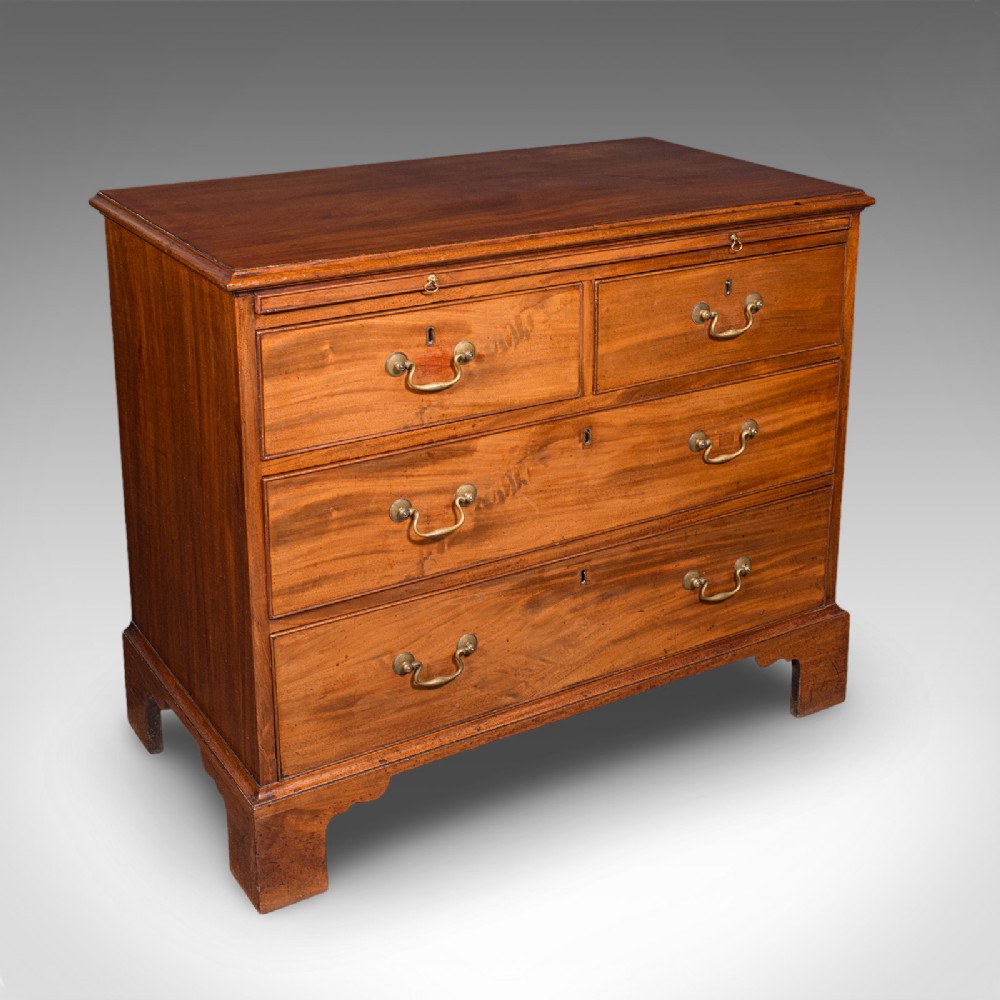 An antique Georgian mahogany bachelors chest featuring a brushing slide above two short and two long drawers with brass swan neck handles and bracket feet.