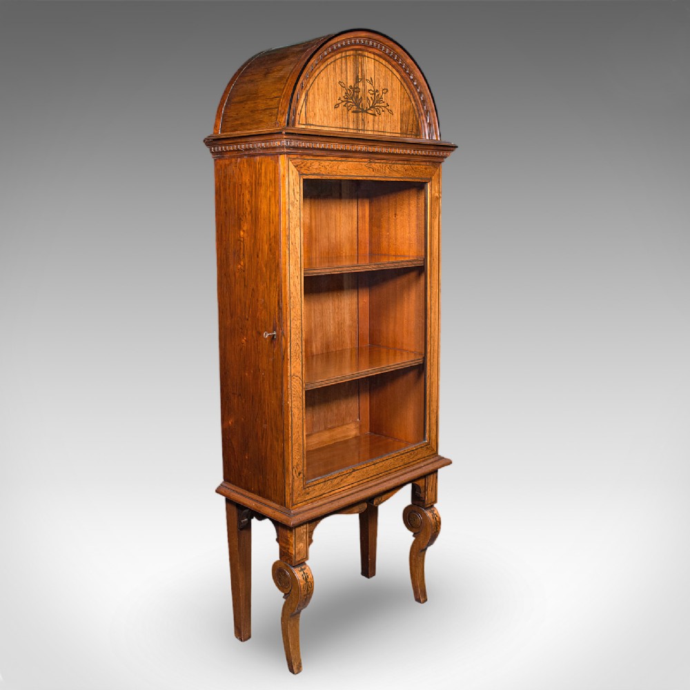 A tall Regency oak display cabinet featuring an arched bonnet top with marquetry inlay, a single glazed door enclosing shelves, and carved front legs.