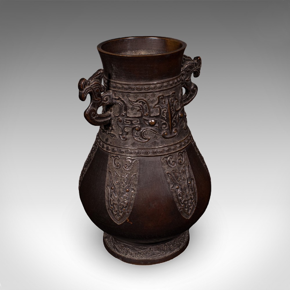 A dark patinated bronze Hu vase featuring archaistic relief carvings and twin dragon handles dating to around 1880.
