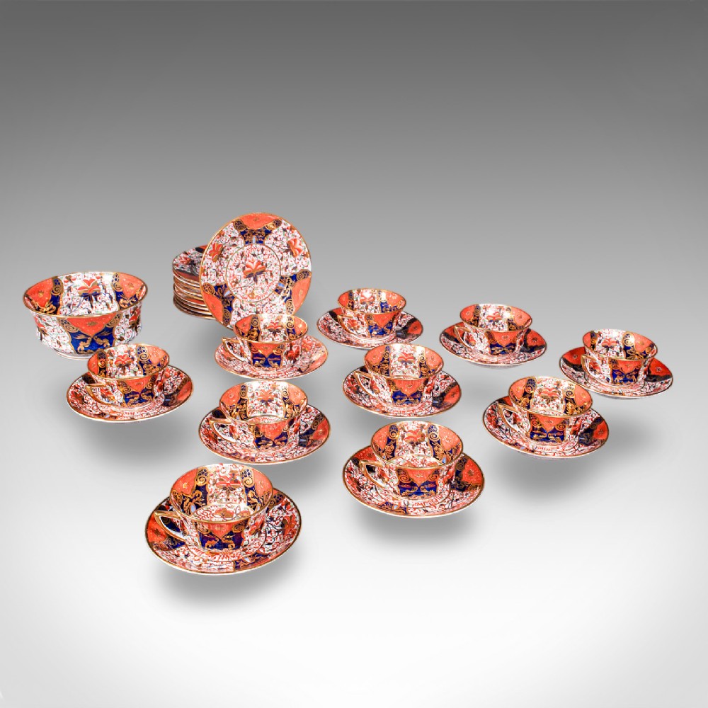 A ten-person Victorian bone china tea service decorated with blue, orange, and gold Imari patterns, featuring teacups, saucers, plates, and a waste bowl.