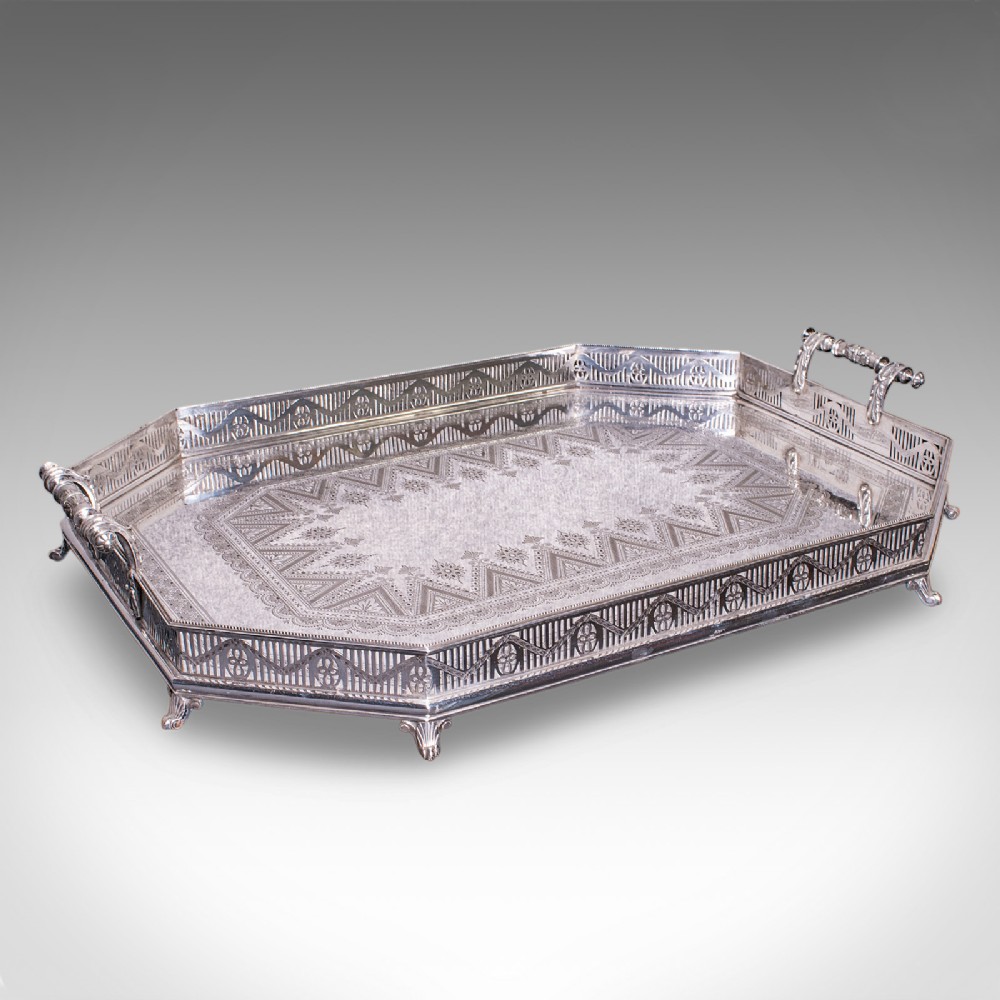 A Victorian silver-plated presentation tray featuring geometric surface engraving, a pierced gallery border, twin side handles, and scroll feet.