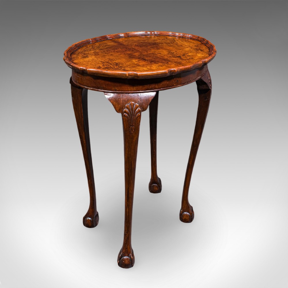 An Edwardian burr walnut oval side table featuring a raised pie crust edge and carved cabriole legs.