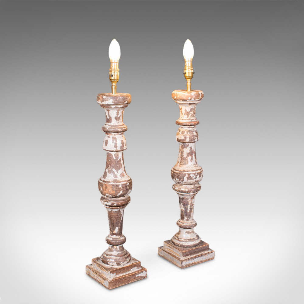 A pair of tall turned pine table lamp bases with heavily distressed grey-white paint revealing natural timber beneath.