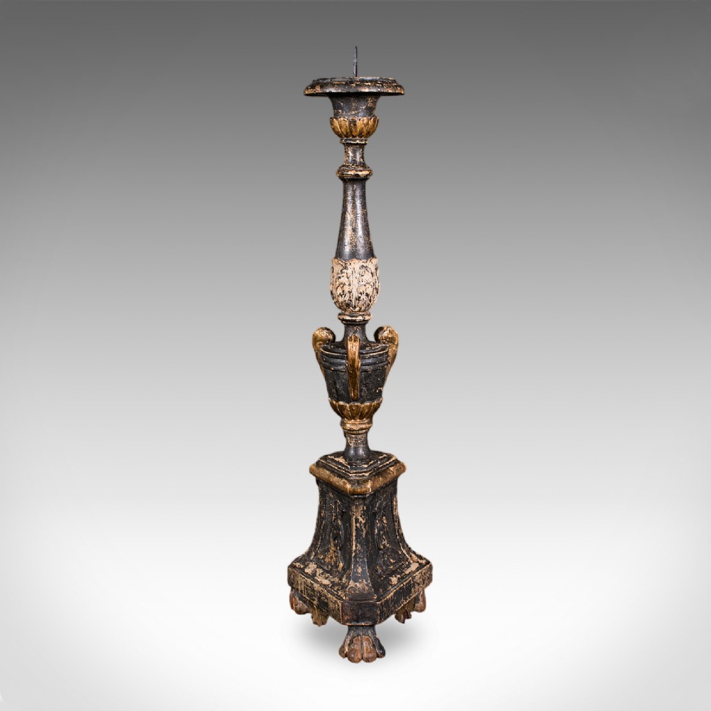A tall Georgian ebonised and giltwood candle pricket featuring a turned baluster stem, urn detail, and a stepped square base resting on claw feet.